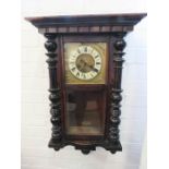 A wall mounted mahogany cased clock with brass and porcelain dial, with key.