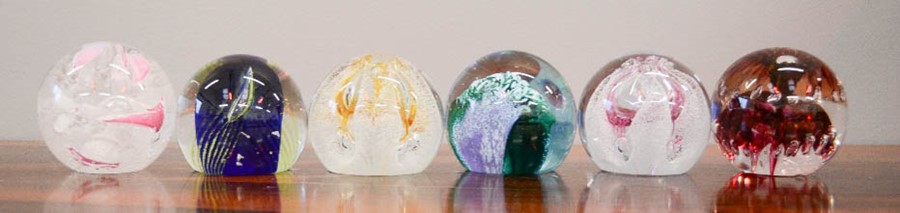 Six glass paperweights, three Caithness examples, and one Langham.