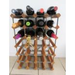 A wooden wine rack, containing bottles of various alcohol, including Navy Rum, red and white wine,