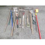 A group of tools to include rakes, apple picker, forks, spades and other items.