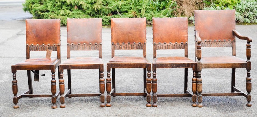 A part set of five oak and leather dining chairs, including one carver chair.