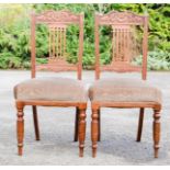 A pair of Edwardian oak carved chairs, with green velour upholstered seats.