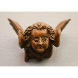 A 19th century carved fruitwood winged angel head, 10cm wide.