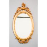 A gold coloured scrollwork oval wall mirror, 84 by 52cm.