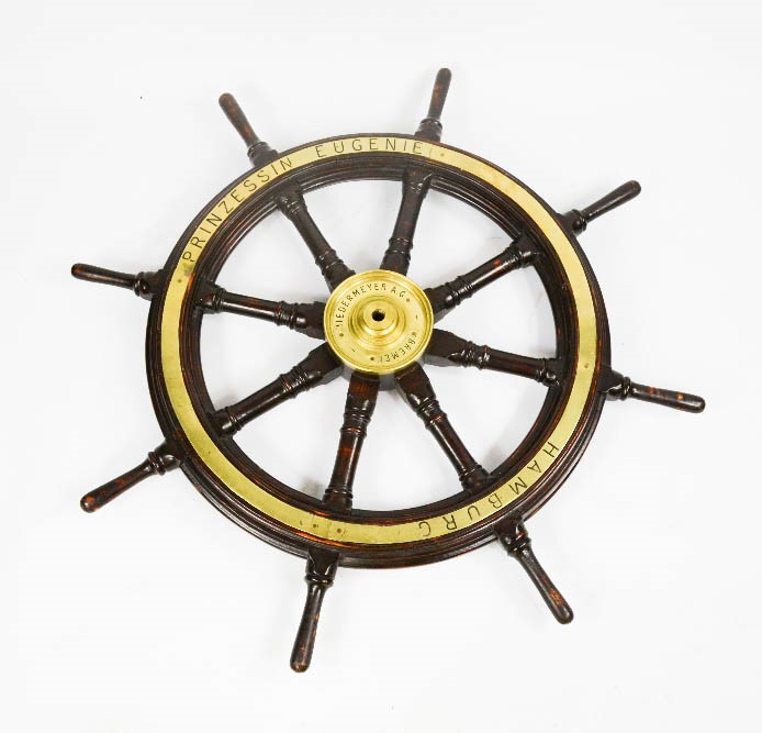 An antique ships wheel, inscribed Prinzessin Eugenie, Hamburg, and to the central brass hub