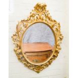 A Venetian giltwood oval wall mirror, carved with scrollwork around the original oval mirror, 100 by