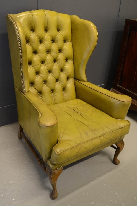 A green leather armchair with buttoned back.