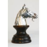 A silver plated watch stand in the form of a horses head raised on a plinth.