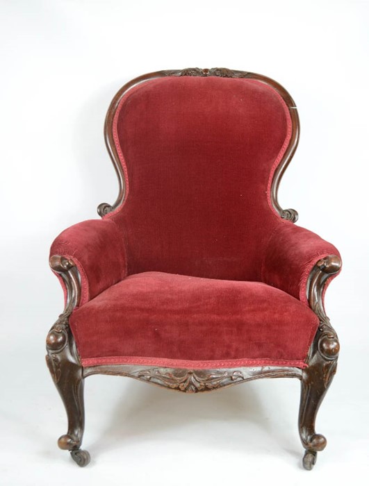 A Victorian mahogany red velvet upholstered armchair, raised on short cabriole legs.