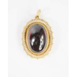 A gilt metal, white enamel and garnet cabochon pendant, 3½cm high, 19.3g.