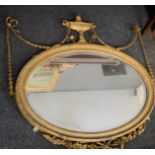 A 19th century Regency giltwood oval mirror the surmounting urn draped with bell flowers and bows,