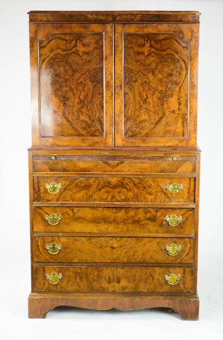 A walnut veneered gentleman's cabinet on chest, the two panelled doors above a brush slide, four