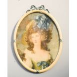 An oval framed print of a young woman, with carved and painted ribbon decoration to the frame,