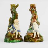 A pair of 19th century Wedgwood majolica candlesticks, in the form of cherubs holding baskets of