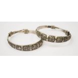 A pair of white metal Chinese bangles, depicting the signs of the zodiac.