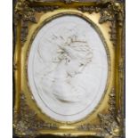 An oval cast plaque depicting a young woman, in a gold painted frame.