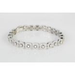 A white metal diamond set bracelet with 24 cushion shaped panels, each set with centre princess