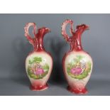 A pair of plum coloured vases, each depicting figural scenes.