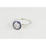 An Art Deco white metal and sapphire bulls eye ring, with central half carat diamond, 2.4g.