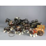 A group of seven ceramic Shire horses with wagons and carts.