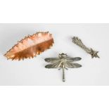 Three brooches; one copper coloured in form of a leaf, a silver starburst and a dragonfly.