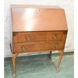 A small mahogany bureau raised on cabriole legs.