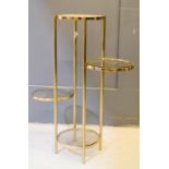 A four tier brass metal occasional table, with circular glass tops of varying height.