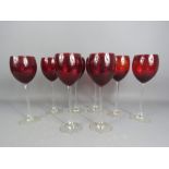 A set of eight red coloured wine glasses.