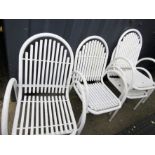 A set of four white metal garden chairs.