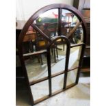 A mirror in the form of an arched window.