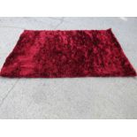 A large modern purple wool rug, and another in red.