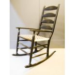 A designer black wooden rocking chair with checkered black and white rush seat.