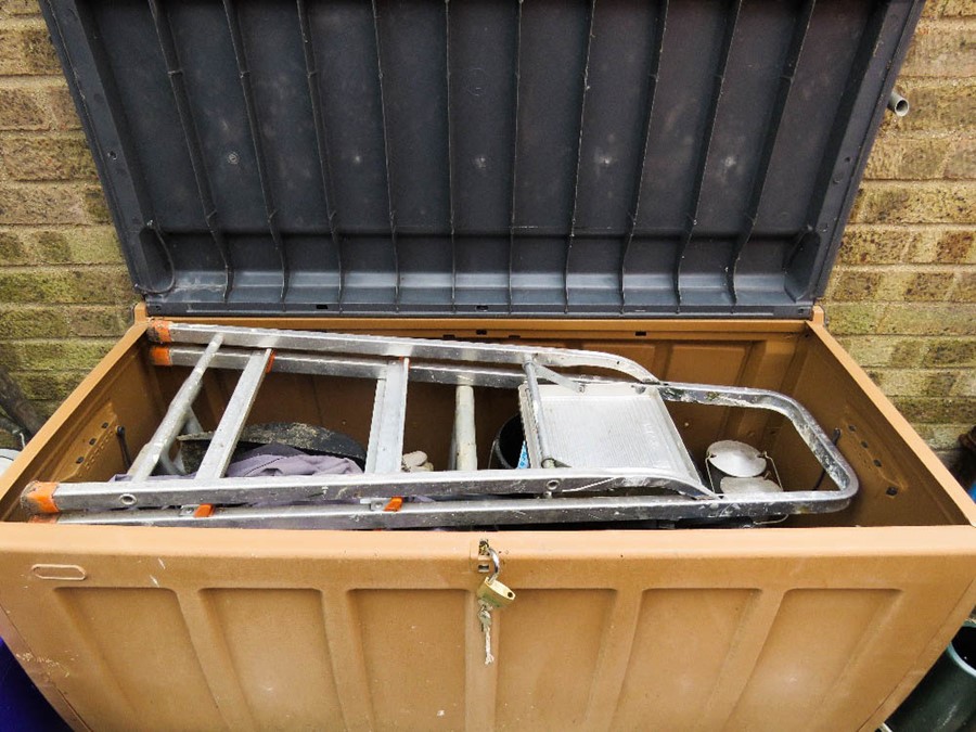 An outdoor garden box containing tools and step ladder.