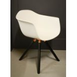 An Eames style white tub chair with rose gold coloured base and black wooden legs.