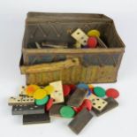 A tin box in the form of a picnic hamper, containing a quantity of bone dominoes and coloured bone