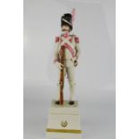 A porcelain figure of a soldier holding a bayonet, signed to the base.