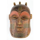 An African carved tribal face mask, painted with detail.