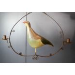 A folk art style tin pheasant, hanging within a shop sign iron candle holder.