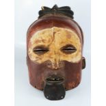 An African carved tribal face mask, painted with detail.