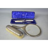 A silver part dressing set, comprising hand mirror, clothes brush, together with a cake knife and