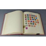 A red stamp album containing worldwide used stamps.