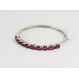 A silver bangle set with pink glass stones.