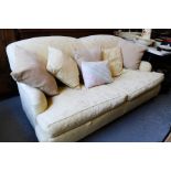 A cream upholstered settee with curved back.