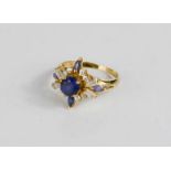 An 18ct gold, sapphire and paste ring, the raised starburst setting with central sapphire of