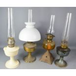 A group of four early 20th century paraffin lamps, one with a white glass shade.