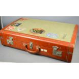 A vintage suitcase, part leather and part canvas, with original airline stickers.