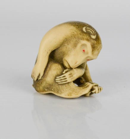 A resin netsuke monkey engraved with detail, 3cm high.