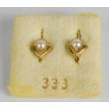 A pair of 9ct gold stud earrings, set with single pearls to the centre within a scalloped bezel.