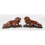 A pair of fruitwood carved lions, inset with bone eyes and teeth, raised on stands, 9cm high.