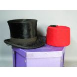 A hat box, fez cap, and an antique ladies riding hat with veil.